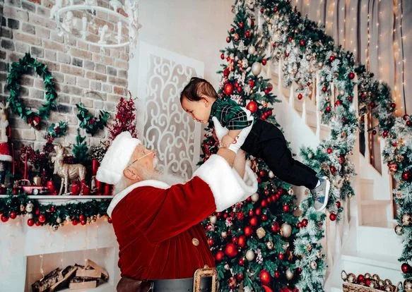 Santa Skip lifting a delighted child near a Christmas tree