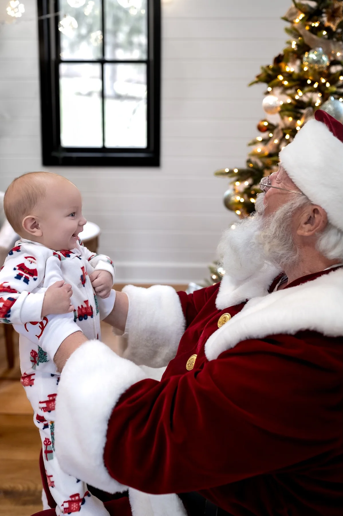 Santa Skip delighting a baby near a Christmas tree