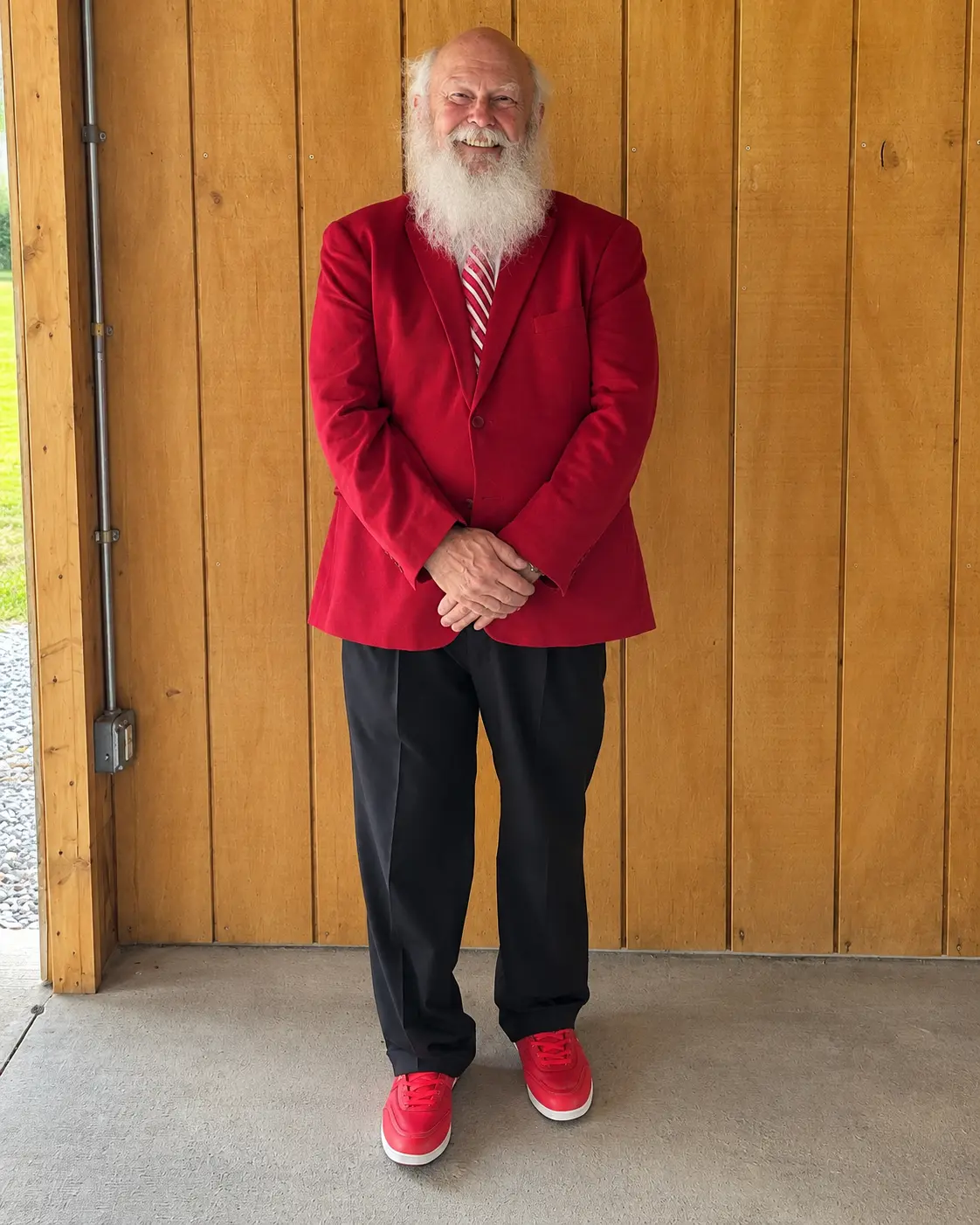 Santa Skip smiling in a polished red blazer, striped tie, dark trousers and red shoes