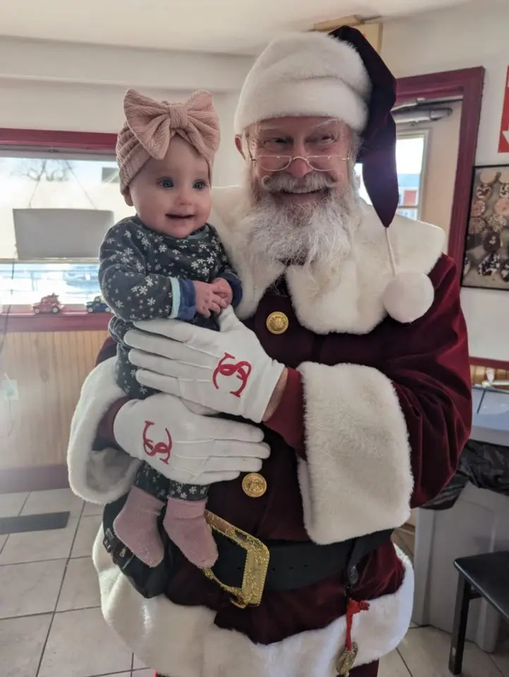 Santa Skip holding a smiling baby during a personal visit